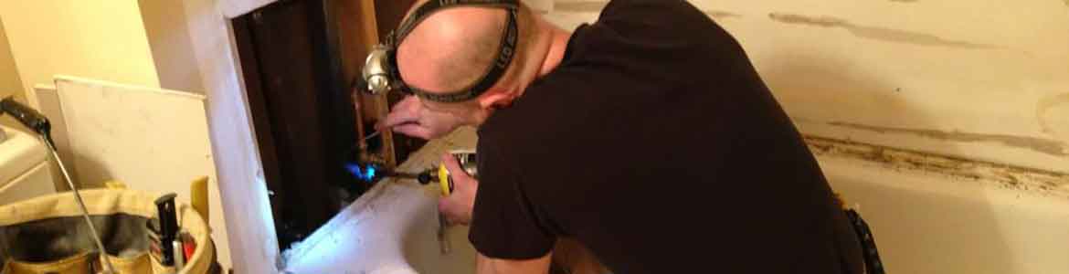 Man working on bathtub plumbing